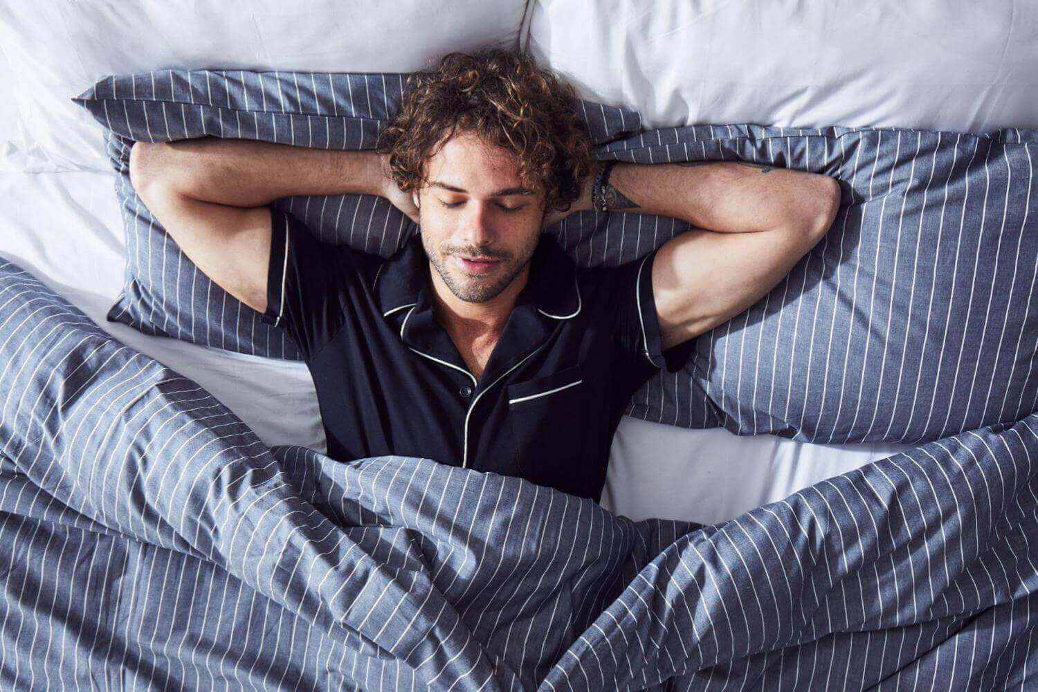 man-sleeping-comfortably-in-navy-striped-bedding