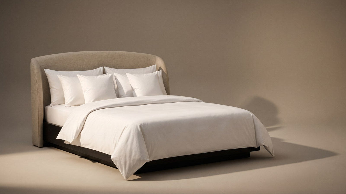Layered UK pillowcases on a made bed, king size at the back, standard housewife in the middle and square pillows at the front