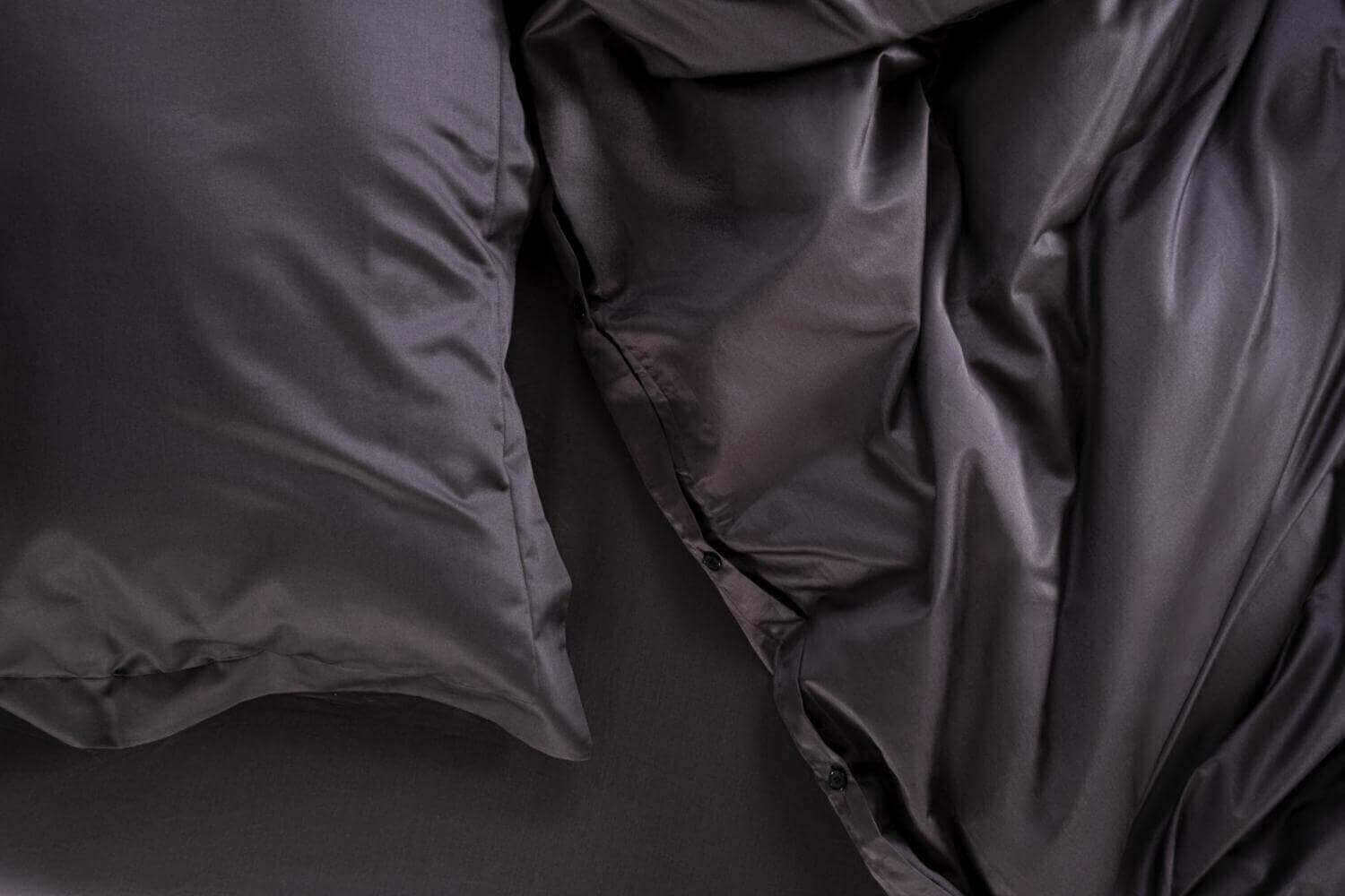 Luxurious black sateen bedding with soft pillows and a smooth comforter.