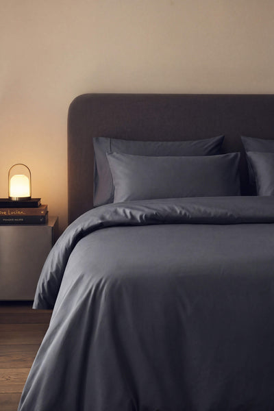 Sateen duvet cover in dark grey on a bed in a softly lit bedroom